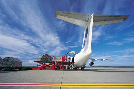A photo of a cargo plane being loaded from behind, on international air transport.